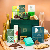 EDEN & CO. Chocolate Hamper letterbox gift with a mini Bottega Gold prosecco, green gift tube, an “Occasion Themed” card, an assortment of chocolate bars, Booja-Booja Chocolate Wonders truffles and chocolate truffles on a small plate, styled against a warm terracotta background.