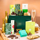 EDEN & CO. Chocolate Hamper letterbox gift with a mini Bottega Gold prosecco, green gift tube, an “Occasion Themed” card, an assortment of chocolate bars, Booja-Booja Chocolate Wonders truffles and chocolate truffles on a small plate, styled against a warm terracotta background.