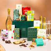 EDEN & CO. Hamper Gift Subscription box with a full-size Bottega Gold prosecco, dark green gift cylinder, an “Occasion Themed” card, a rotating selection of chocolates, truffles and treats, styled with gold silk against a warm terracotta background.