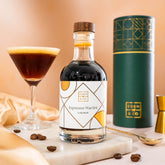 EDEN & CO. liqueur gift bottle with an “Occasion Themed” card, presented in a branded gift tube, styled with gold silk against a warm terracotta background.