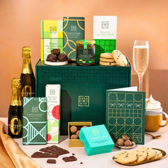 EDEN & CO. Chocolate Hamper letterbox gift with a mini Bottega Zero Black prosecco (0% alcohol-free), green gift tube, an “Occasion Themed” card, an assortment of chocolate bars, Booja-Booja Chocolate Wonders truffles and chocolate truffles on a small plate, styled against a warm terracotta background.
