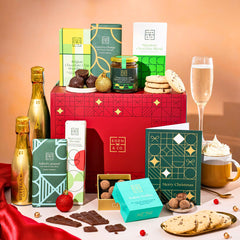 EDEN & CO. Chocolate Hamper letterbox gift with a mini Bottega Gold prosecco, green gift tube, an “Occasion Themed” card, an assortment of chocolate bars, Booja-Booja Chocolate Wonders truffles and chocolate truffles on a small plate, styled against a warm terracotta background.