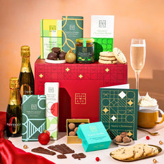 EDEN & CO. Chocolate Hamper letterbox gift with a mini Bottega Zero Black prosecco (0% alcohol-free), green gift tube, an “Occasion Themed” card, an assortment of chocolate bars, Booja-Booja Chocolate Wonders truffles and chocolate truffles on a small plate, styled against a warm terracotta background.